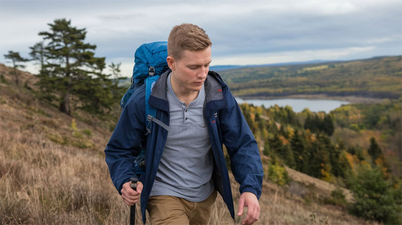 young single man hiking a hill on a cloudy day